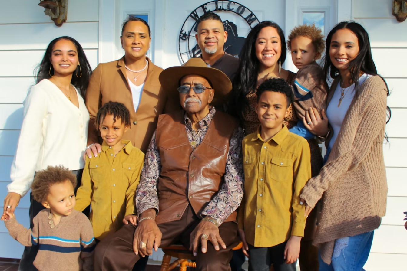 A three-generation family posing together outside their home