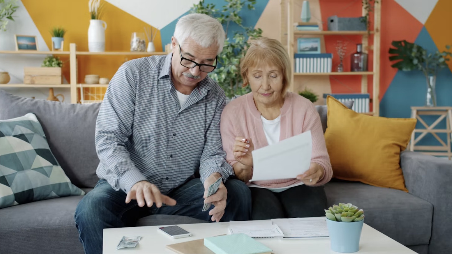 A senior couple reviewing paperwork together on their couch